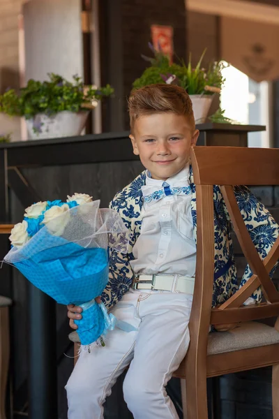 Çiçeklerle restoranda oturan sevimli küçük çocuk