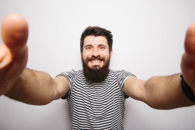 Beyaz izole arka plan üzerinde duran ve kamera elleri ile selfie çekerek sakallı mutlu gülümseyen hipster adam.