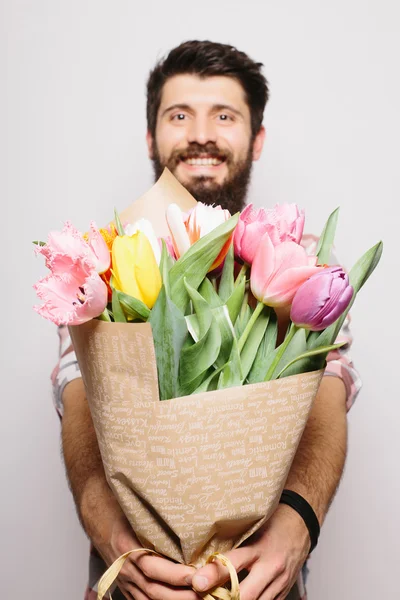 Retrato Joven guapo con barba y bonito ramo de flores sobre fondo blanco — Foto de Stock