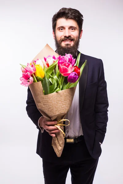 Beau jeune homme en costume, avec barbe et beau bouquet de fleurs sur fond blanc — Photo