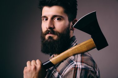 Genç adam büyük balta ve kameraya bakarak sakallı