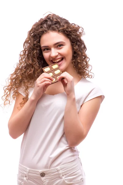 Retrato de uma jovem menina bonita com cabelo encaracolado, segurando uma barra de chocolate — Fotografia de Stock