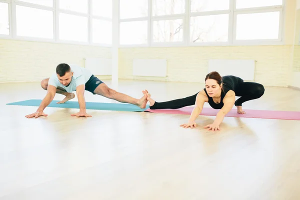 Atractive yoga couple , man and woman, practice exercises in a training hall