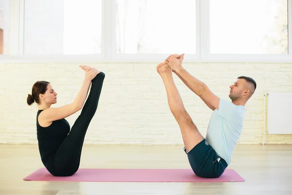 Atractive yoga par, man och kvinna, öva övningar i en utbildning hall — Stockfoto