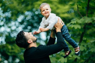mutlu neşeli baba eğleniyor havada küçük çocuğunu atar,