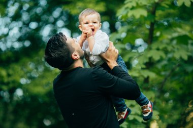 mutlu neşeli baba eğleniyor havada küçük çocuğunu atar,