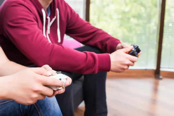 Two handsome young men playing video games while sitting on sofa — Stock Photo, Image