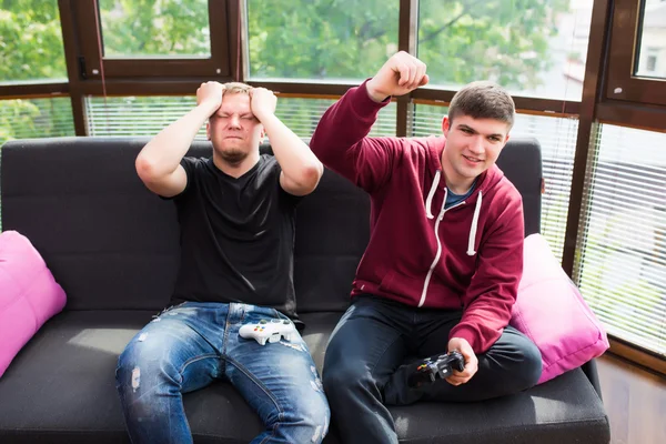 Twee knappe jonge mannen spelen van videospellen zittend op de Bank — Stockfoto