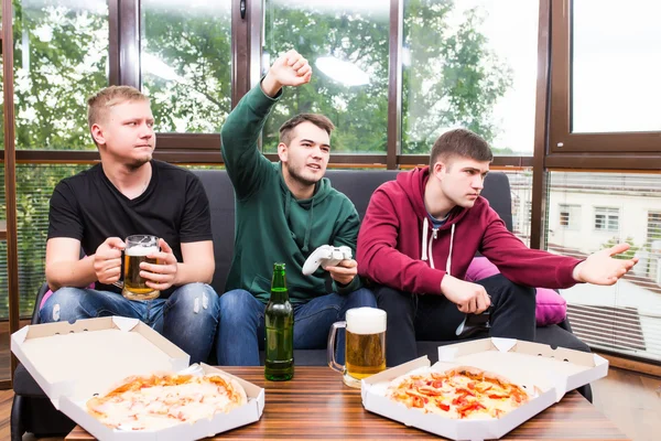 Amigos masculinos sonrientes jugando videojuegos, beber cerveza y divertirse en casa —  Fotos de Stock