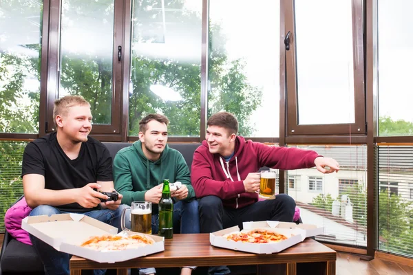 Amigos masculinos sonrientes jugando videojuegos, beber cerveza y divertirse en casa —  Fotos de Stock