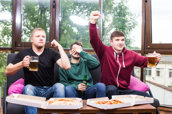 Χαμογελώντας αρσενικούς φίλους παίζοντας βιντεοπαιχνίδια, πίνουν μπίρα και να διασκεδάσουν στο σπίτι — Φωτογραφία Αρχείου