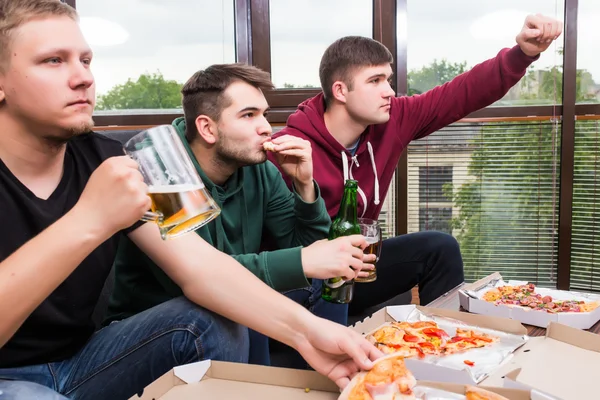 Tres jóvenes felices viendo el partido de fútbol y manteniendo los brazos levantados —  Fotos de Stock