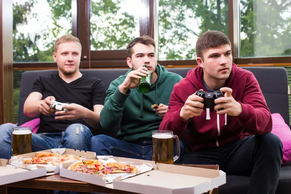 Three happy young men watching football game and keeping arms raised — Stock Photo, Image
