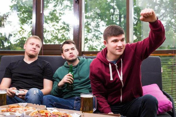 Tres jóvenes felices viendo el partido de fútbol y manteniendo los brazos levantados —  Fotos de Stock