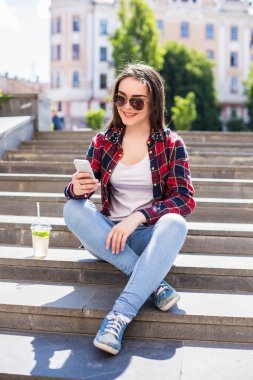 merdivenlerde oturan ve iletişim için onun smartphone kullanarak yeni bir fincan kadınla.