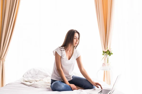 pretty girl looking at laptop monitor while lying on bed in her room