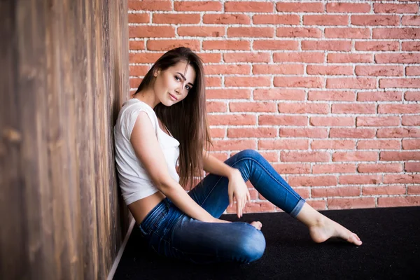 Дівчина сидить на дерев'яній і цегляній стіні — стокове фото
