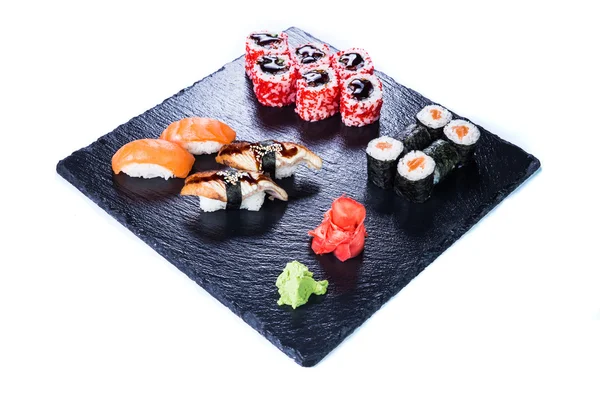 Sushi Set a suši se valí na černý kámen břidlice. — Stock fotografie