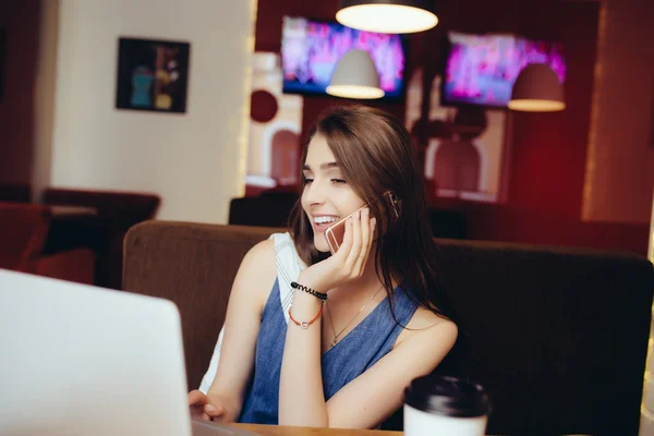 Vrouw die op laptop werkt en praten over de telefoon in de coffeeshop — Stockfoto