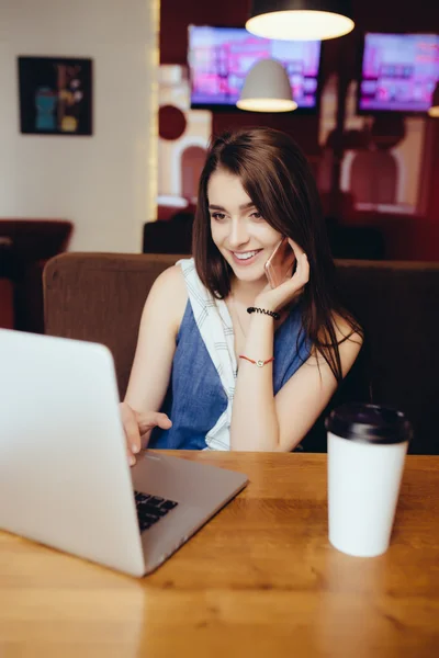 Kobieta pracuje na laptopie i rozmawia przez telefon w kawiarni — Zdjęcie stockowe