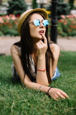 çimenlerin üzerinde yaz günü şehir parkında yalan güneş gözlüklü kız.