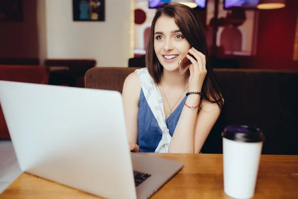 Vrouw die op laptop werkt en praten over de telefoon in de coffeeshop — Stockfoto