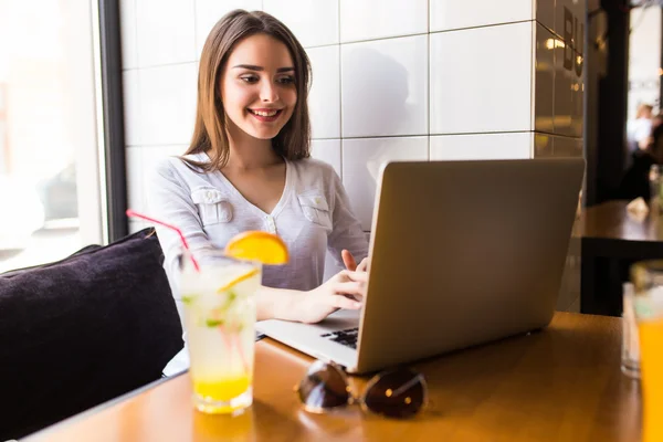 Meisje met laptop en drinken vers in café — Stockfoto