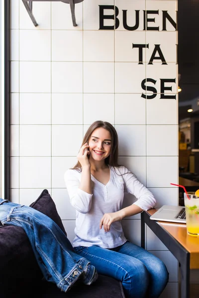 휴대 전화에 현대 커피숍 인테리어에 혼자 앉아있는 동안 친구와 얘기 하는 여자 — 스톡 사진