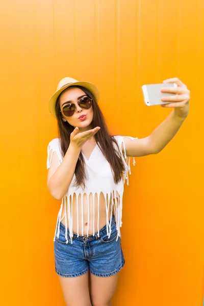 Mulher faz auto-retrato no smartphone sobre cor da cidade parede fundo — Fotografia de Stock