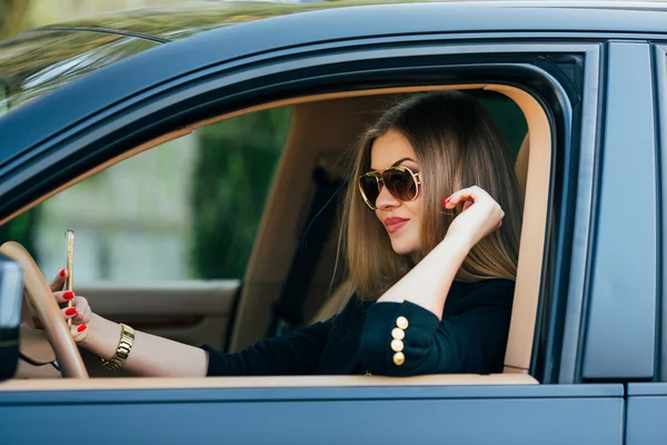 Mujer joven en gafas de sol detrás del volante — Foto de Stock