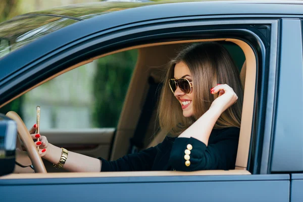 Mujer joven en gafas de sol detrás del volante — Foto de Stock