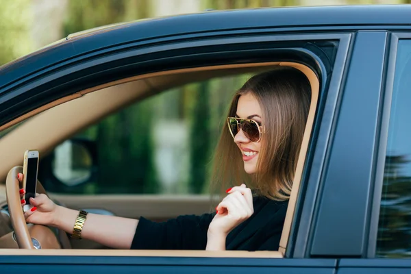 Mujer joven en gafas de sol detrás del volante — Foto de Stock