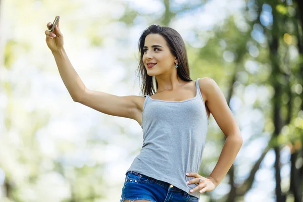 Fiatal nő selfie a parkban egy smartphone — Stock Fotó