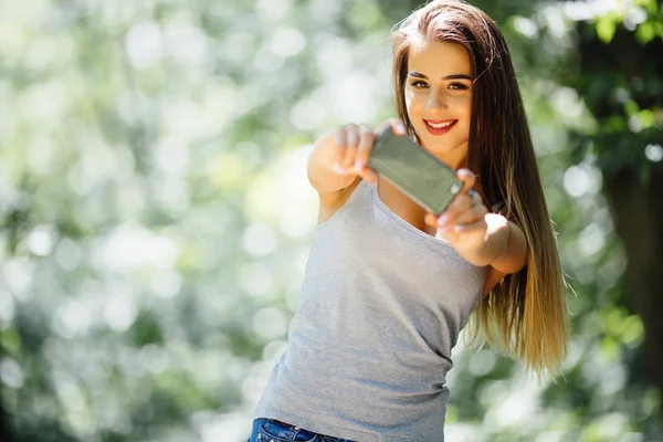 Jovem selfie mulher no parque com um smartphone — Fotografia de Stock