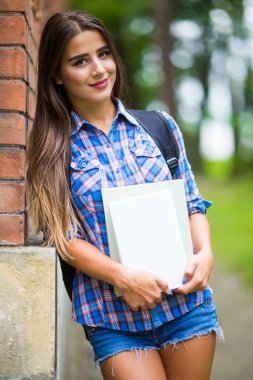 gülümseyen üniversiteli kız kitap tutuyor