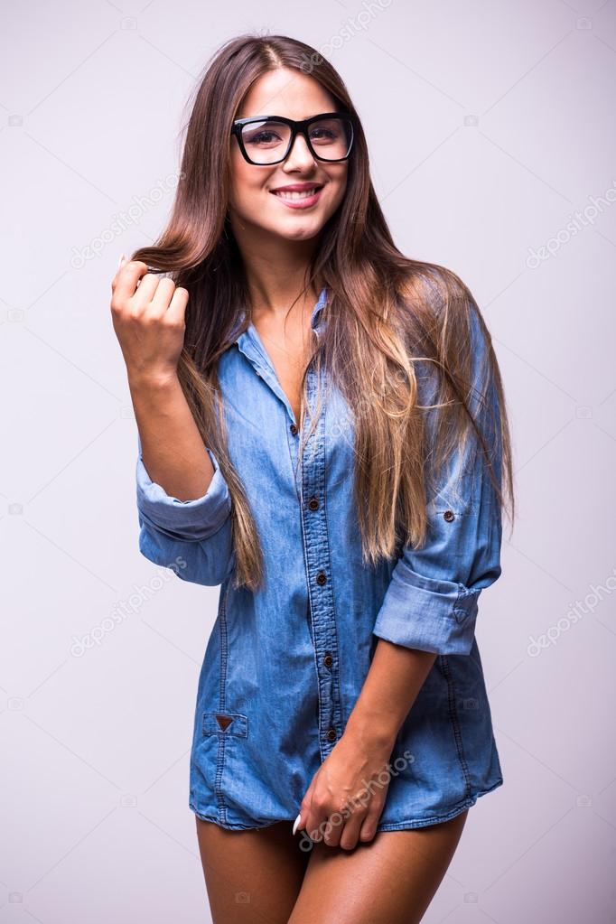 Stylish lady in casual shirt and jeans strikes selfie pose, holds  smartphone, gently touches face, isolated on blue background. 25863421  Stock Photo at Vecteezy