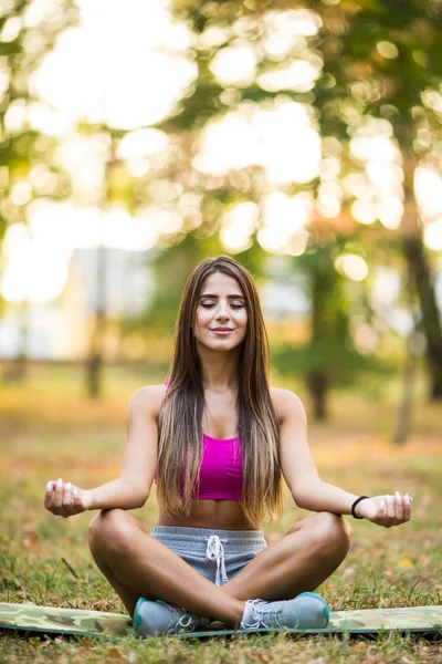 Jeune femme faisant du yoga dans le parc — Photo