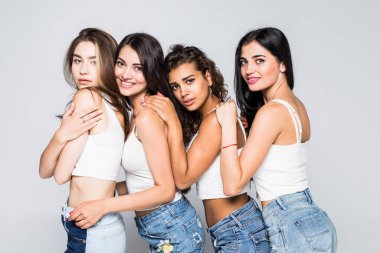 Beyaz arka planda izole edilmiş ve kameraya bakan dört mutlu kadının tam boy portresi.