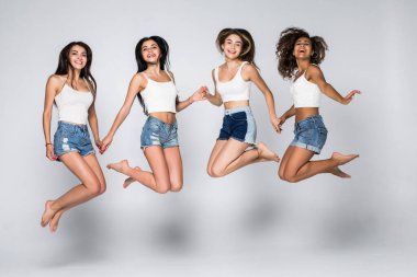 Bir grup neşeli genç kız havaya zıplıyor. Beyaz arkaplanda izole