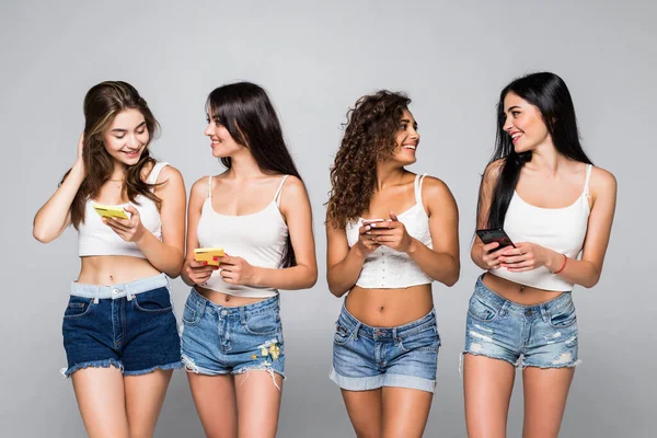 四个身穿白衬衫和短裤的小女孩站在白底电话上聊天 — 图库照片