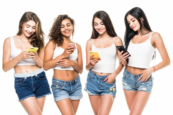 若いです4人の女性のシャツとショートパンツは白い背景に携帯電話で立って — ストック写真