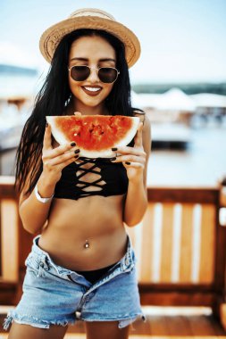 Genç bir kadın tatilde havuzda taze karpuz yiyor.