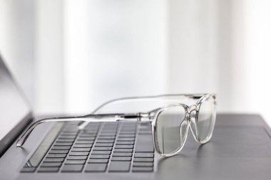 Gözlükler dizüstü bilgisayarda, klavyede, ahşap masada.