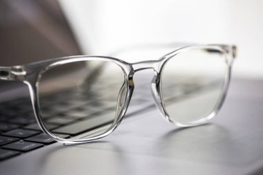 Gözlükler dizüstü bilgisayarda, klavyede, ahşap masada.