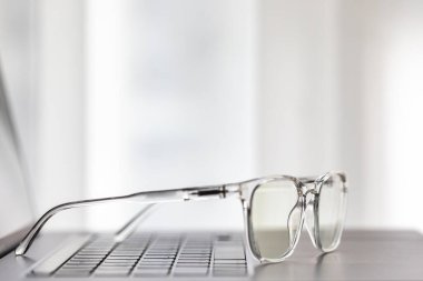 Gözlükler dizüstü bilgisayarda, klavyede, ahşap masada.