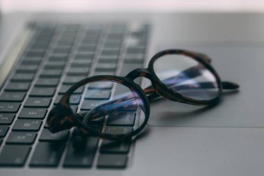 Gözlükler dizüstü bilgisayarda, ahşap masada, kapat.