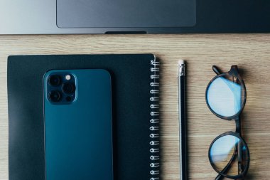 Telefon, gözlük, günlük ve kalem ahşap masa manzarasında.
