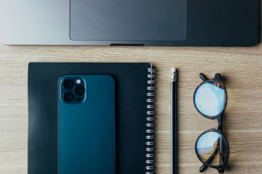 Telefon, gözlük, günlük ve kalem ahşap masa manzarasında.
