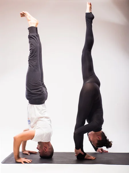 Jeune couple en bonne santé en position de yoga sur fond blanc — Photo