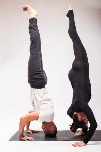 Jeune couple en bonne santé en position de yoga sur fond blanc — Photo